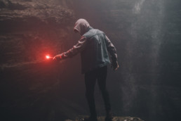 man on edge of cliff holding signal flare light